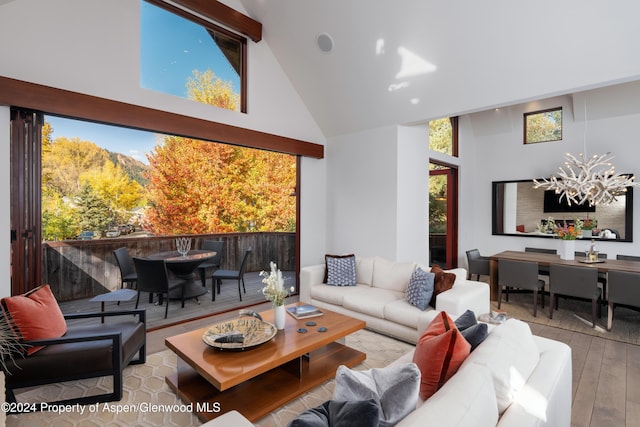 living area featuring a notable chandelier, wood-type flooring, and high vaulted ceiling