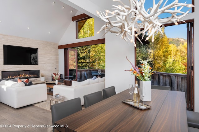 dining space with hardwood / wood-style floors, high vaulted ceiling, plenty of natural light, and a chandelier