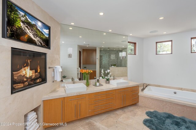 bathroom with a sink, a garden tub, double vanity, and a shower stall