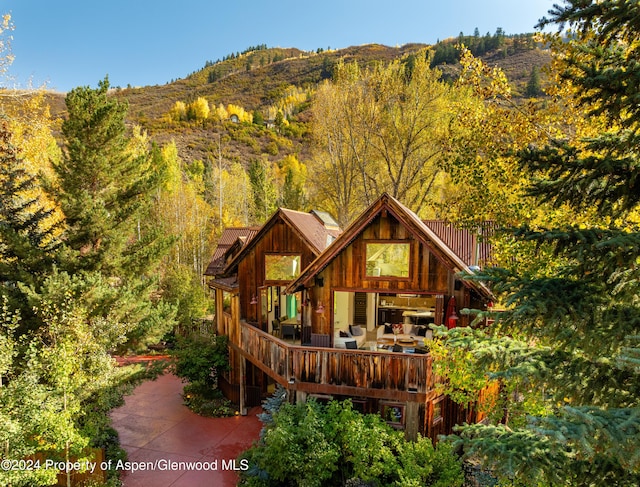 rear view of property with a wooded view and a mountain view