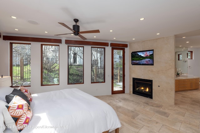 bedroom featuring a tiled fireplace, recessed lighting, ensuite bath, and access to outside