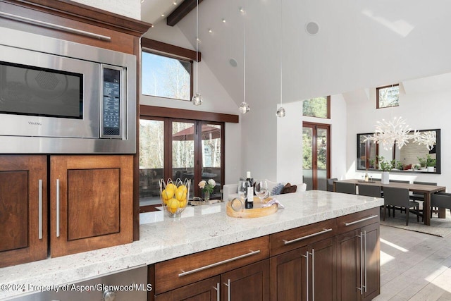 kitchen with light stone countertops, beam ceiling, french doors, stainless steel microwave, and light wood-type flooring