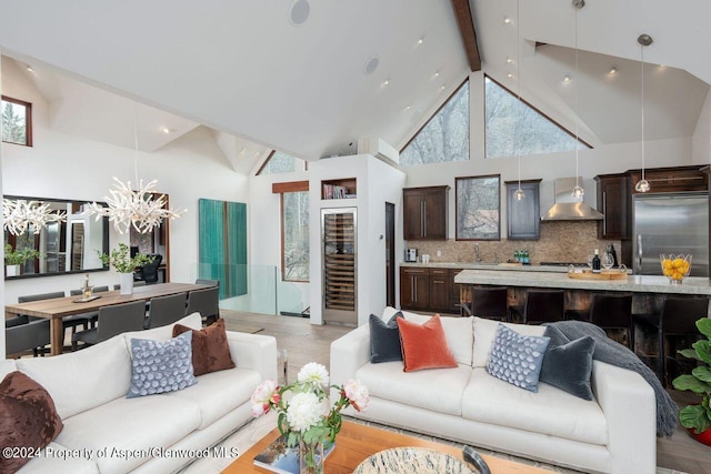 living area with light wood-type flooring, beam ceiling, high vaulted ceiling, wine cooler, and a chandelier