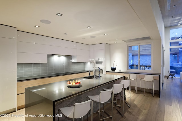 126 Juan St, Aspen, CO 81611 - kitchen with modern cabinets, light wood-style floors, a kitchen bar, white cabinets, and recessed lighting