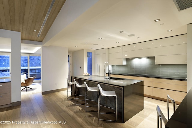 126 Juan St, Aspen, CO 81611 - kitchen featuring modern cabinets, a breakfast bar, dark countertops, light wood finished floors, and recessed lighting