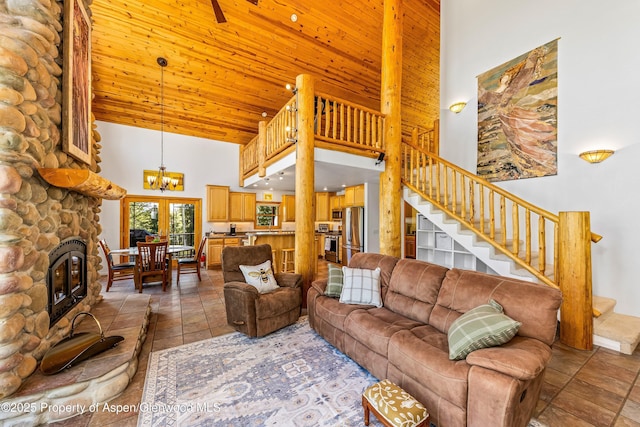 180 Ridge Rd, Gunnison, CO 81230 - tiled living area with high vaulted ceiling, stairs, a chandelier, and a stone fireplace