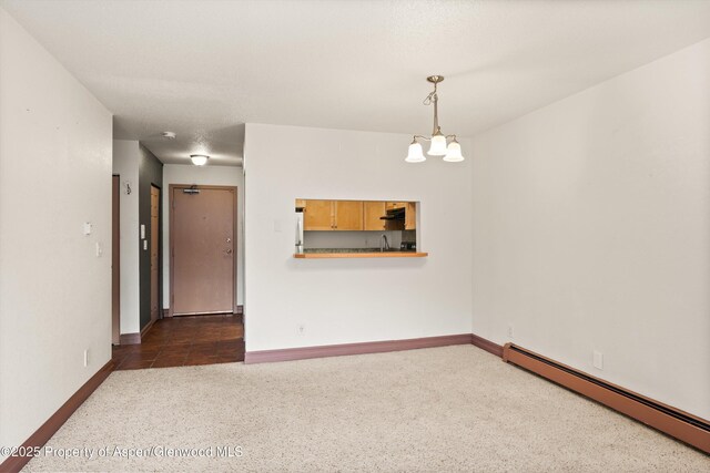 1527 Blake Ave Unit 209, Glenwood Springs, CO 81602 - unfurnished room featuring baseboard heating, dark colored carpet, and a chandelier