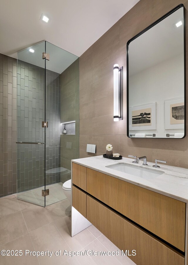 810 W Smuggler St, Aspen, CO 81611 - full bath featuring tile walls, toilet, vanity, a stall shower, and tile patterned floors