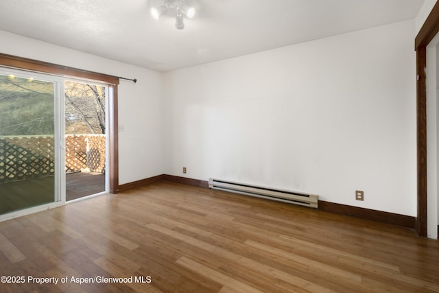 empty room featuring wood-type flooring and a baseboard heating unit