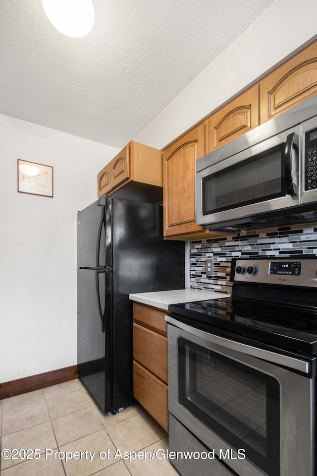 kitchen featuring backsplash, light tile patterned floors, a textured ceiling, and appliances with stainless steel finishes