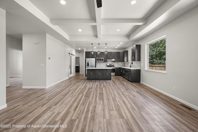 964 E 17th St, Rifle, CO 81650 - kitchen featuring appliances with stainless steel finishes, a sink, light countertops, dark cabinetry, and a kitchen island