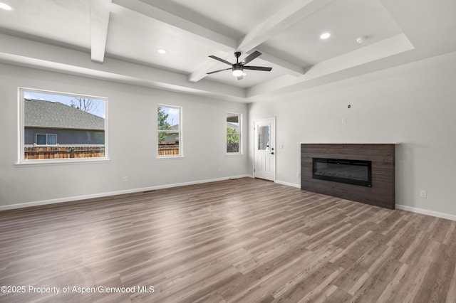 964 E 17th St, Rifle, CO 81650 - unfurnished living room with wood finished floors, beam ceiling, a glass covered fireplace, recessed lighting, and baseboards
