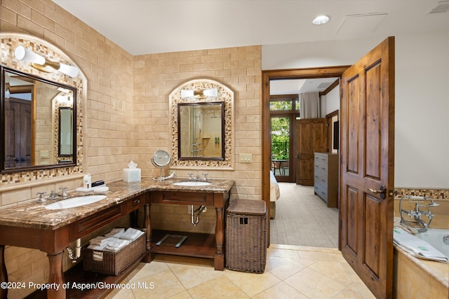 bathroom featuring tile patterned flooring, vanity, a tub to relax in, and tile walls