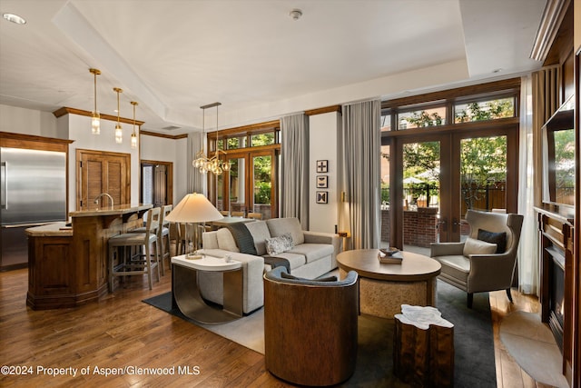 living room with a raised ceiling, dark wood-type flooring, and french doors