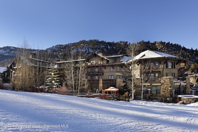 snow covered rear of property with a mountain view