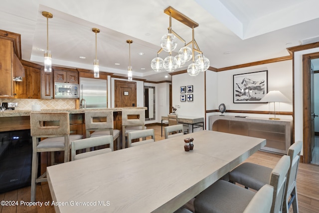 dining area with a raised ceiling, light hardwood / wood-style floors, and crown molding