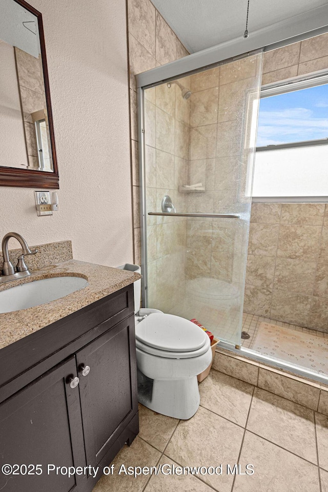 194 Hill Dr, Craig, CO 81625 - bathroom featuring a shower stall, toilet, tile patterned floors, vanity, and a textured wall