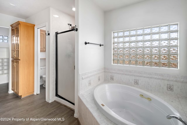 bathroom with hardwood / wood-style flooring, toilet, and shower with separate bathtub