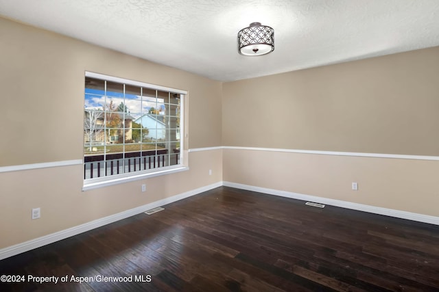 spare room with a textured ceiling and dark wood-type flooring