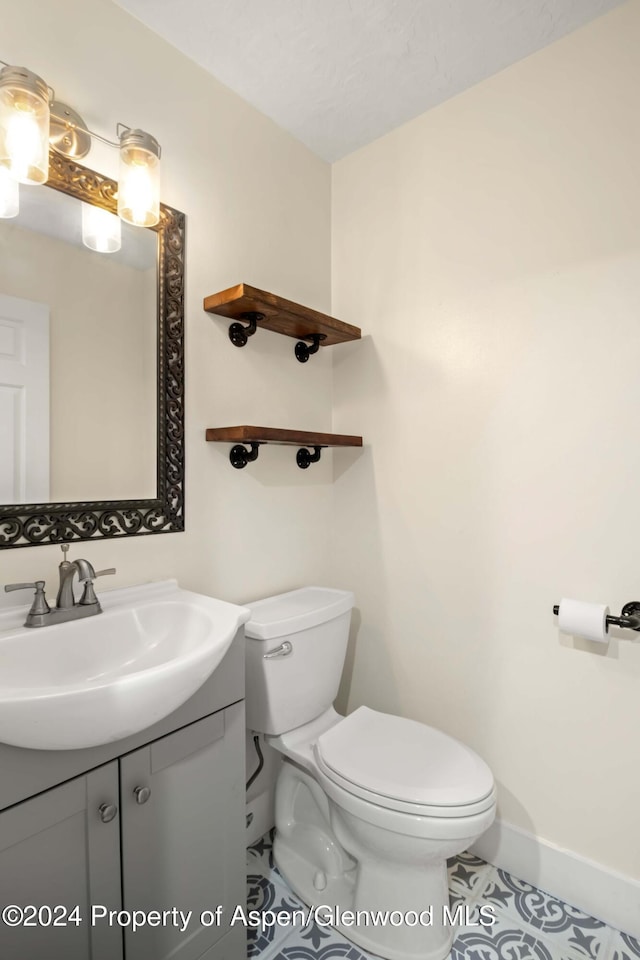 bathroom with tile patterned flooring, vanity, and toilet