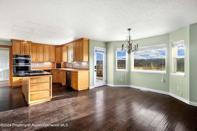 kitchen with decorative light fixtures, appliances with stainless steel finishes, a notable chandelier, a kitchen island, and dark hardwood / wood-style flooring