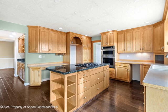 kitchen featuring light brown cabinets, dark wood-type flooring, stainless steel double oven, black gas stovetop, and a kitchen island