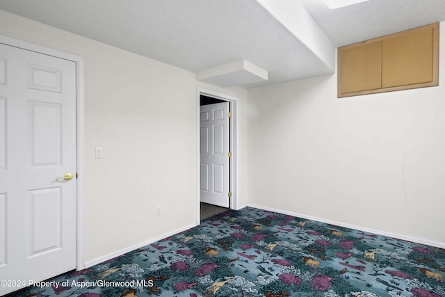 interior space featuring dark colored carpet and a textured ceiling