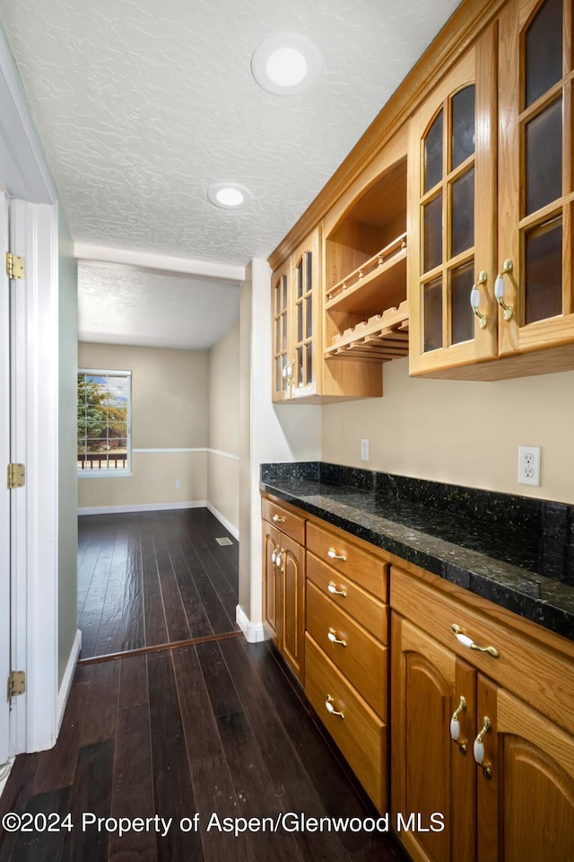 kitchen featuring dark stone countertops, dark hardwood / wood-style flooring, and a textured ceiling