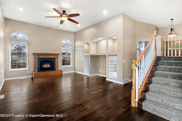 unfurnished living room featuring built in shelves, ceiling fan, and dark wood-type flooring