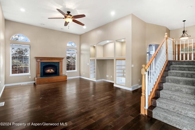 unfurnished living room featuring built in shelves, ceiling fan, and dark wood-type flooring