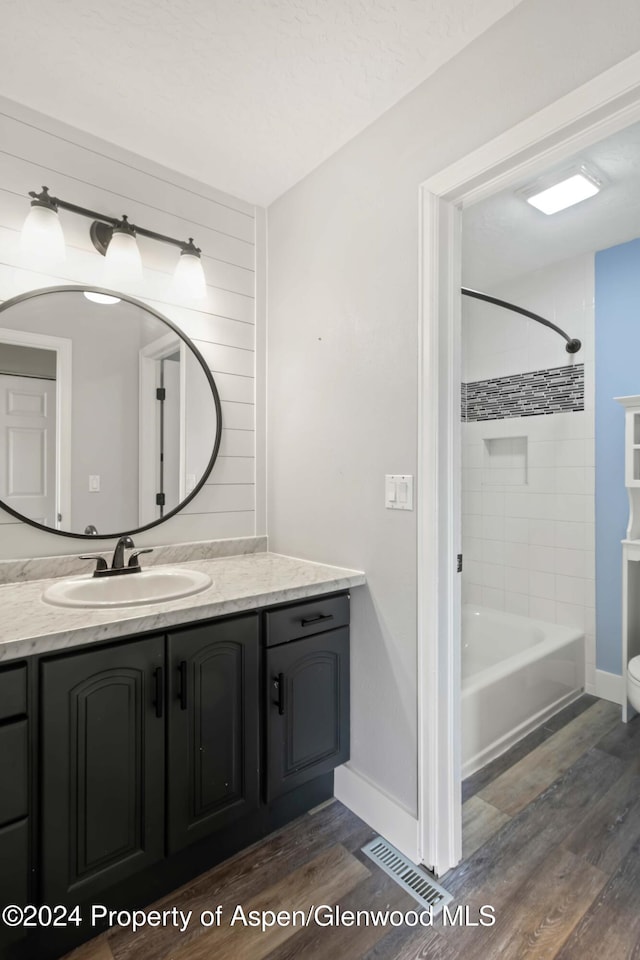 bathroom featuring wood-type flooring, vanity, and tiled shower / bath combo