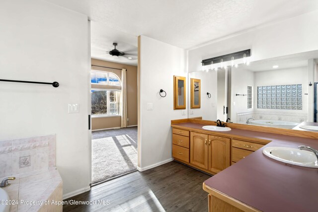 bathroom with ceiling fan, wood-type flooring, a tub to relax in, and vanity