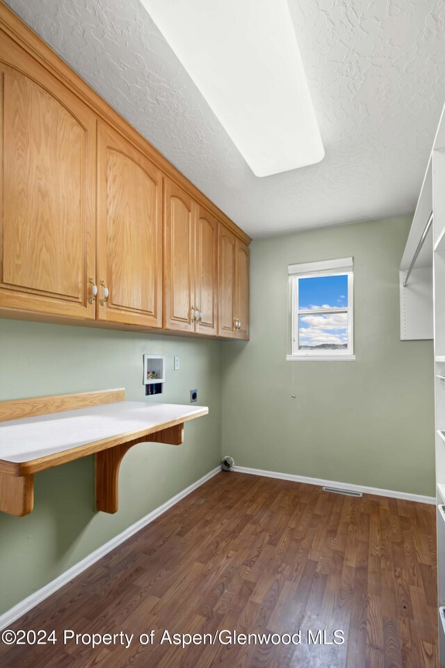 washroom featuring cabinets, washer hookup, a textured ceiling, hookup for an electric dryer, and dark hardwood / wood-style flooring