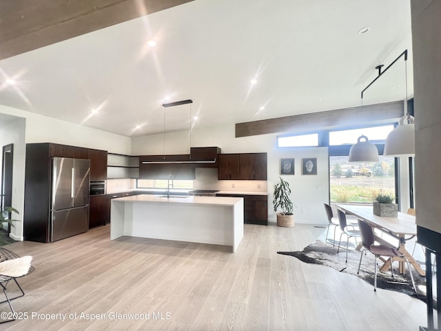 kitchen featuring dark brown cabinets, pendant lighting, stainless steel refrigerator, and light hardwood / wood-style flooring