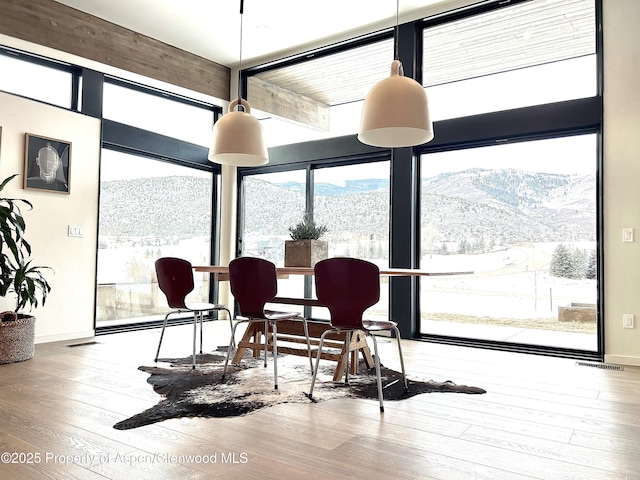 dining room featuring a mountain view, hardwood / wood-style floors, and a wall of windows