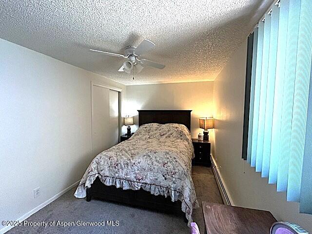 204 W 12th St, Craig, CO 81625 - bedroom featuring a baseboard radiator, carpet floors, a textured ceiling, and a ceiling fan
