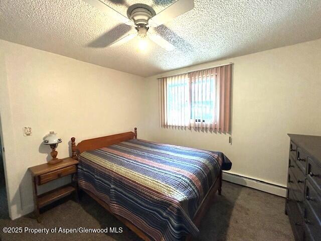 204 W 12th St, Craig, CO 81625 - carpeted bedroom with a baseboard heating unit, a textured ceiling, and ceiling fan