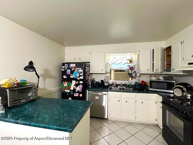204 W 12th St, Craig, CO 81625 - kitchen with black appliances, white cabinets, dark countertops, light tile patterned floors, and under cabinet range hood