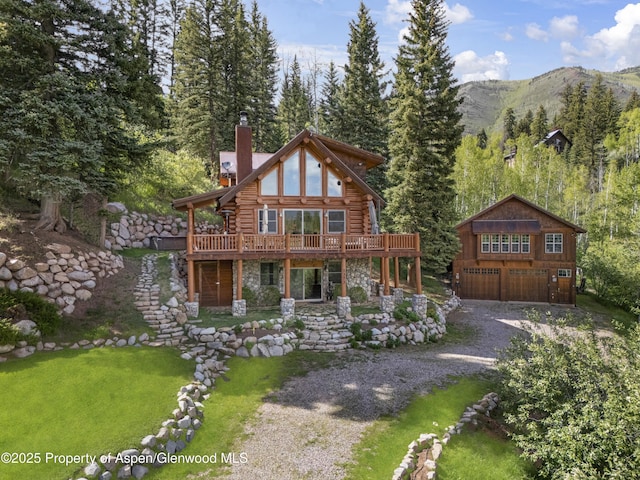 1373 Mclaughlin Ln, Basalt, CO 81621 - view of front of property featuring a chimney, a deck with mountain view, log exterior, a detached garage, and stone siding