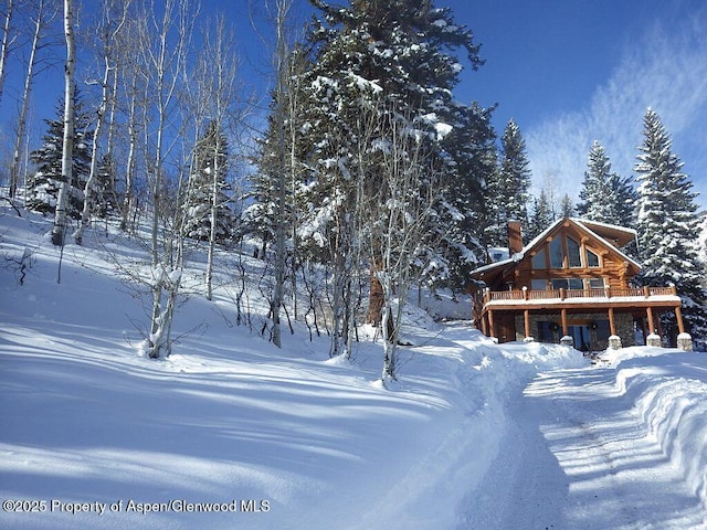 1373 Mclaughlin Ln, Basalt, CO 81621 - snow covered back of property featuring a chimney, a wooden deck, and log exterior