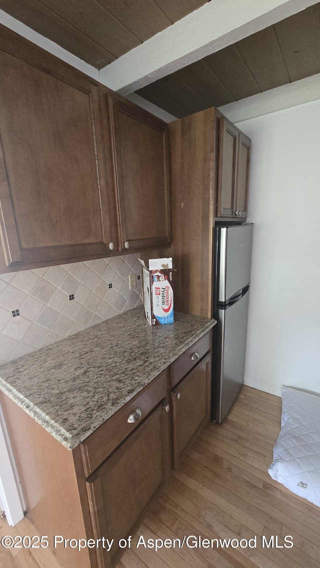 35 Campground Ln Unit E4, Snowmass Village, CO 81615 - kitchen featuring freestanding refrigerator, tasteful backsplash, light wood finished floors, and light stone countertops