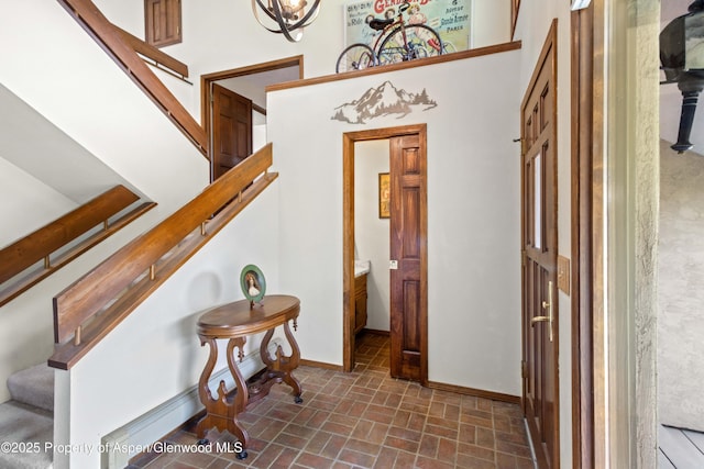 entrance foyer featuring stairs, brick patterned floor, and baseboards
