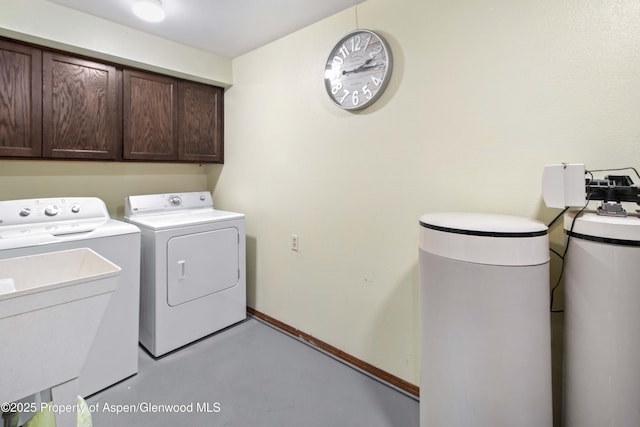 clothes washing area with separate washer and dryer, cabinet space, and baseboards