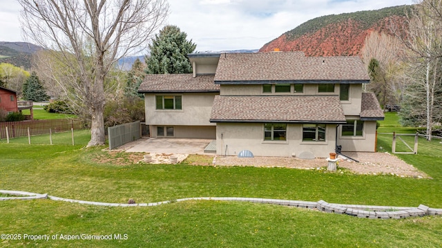 back of house with a mountain view, a shingled roof, a fenced backyard, and a patio area
