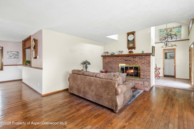 living room featuring hardwood / wood-style floors, baseboards, wallpapered walls, and a brick fireplace