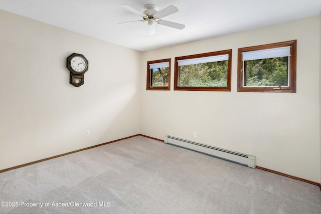 spare room featuring a baseboard heating unit, ceiling fan, light colored carpet, and baseboards