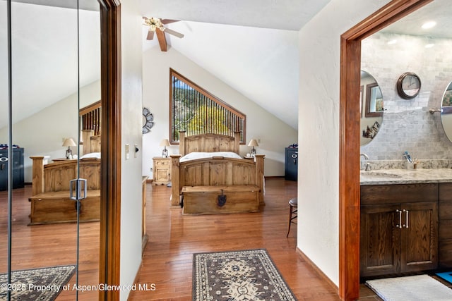 bedroom with lofted ceiling, wood finished floors, and a sink