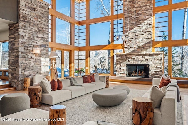 living room with a stone fireplace, wood-type flooring, and a high ceiling