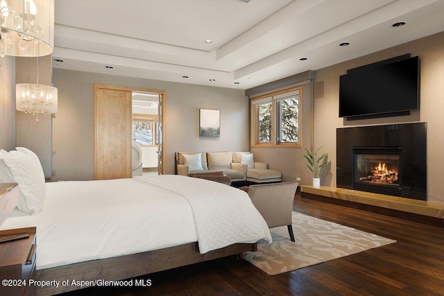 bedroom with a raised ceiling, dark wood-type flooring, and a notable chandelier