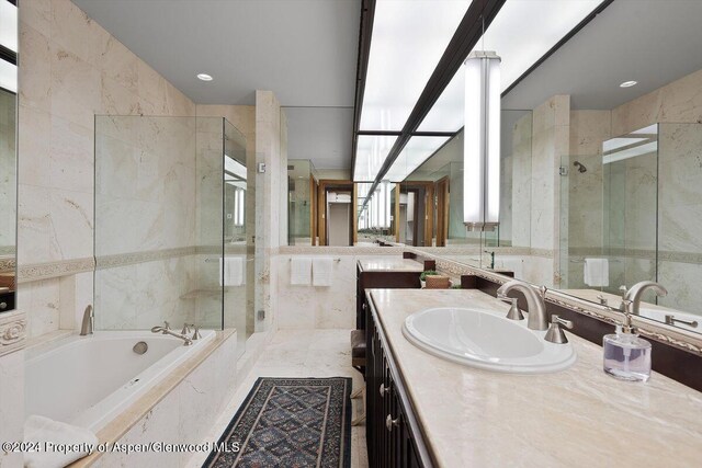 bathroom with vanity, separate shower and tub, and tile walls